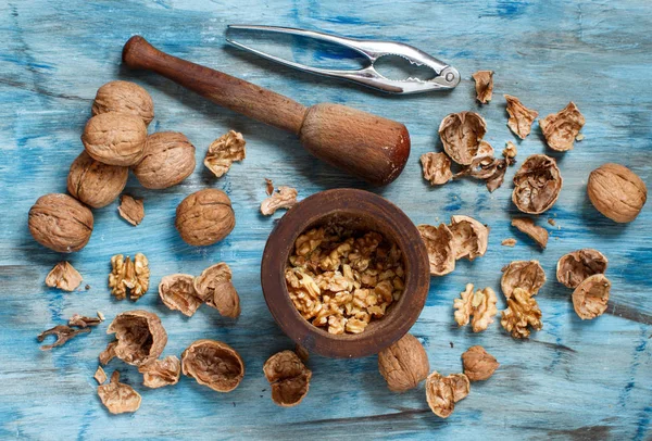 Nueces frescas y mortero sobre una mesa de madera azul — Foto de Stock