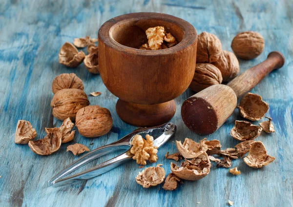 Nueces frescas y mortero sobre una mesa de madera azul — Foto de Stock