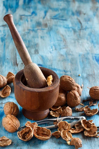 Nueces frescas y mortero sobre una mesa de madera azul — Foto de Stock