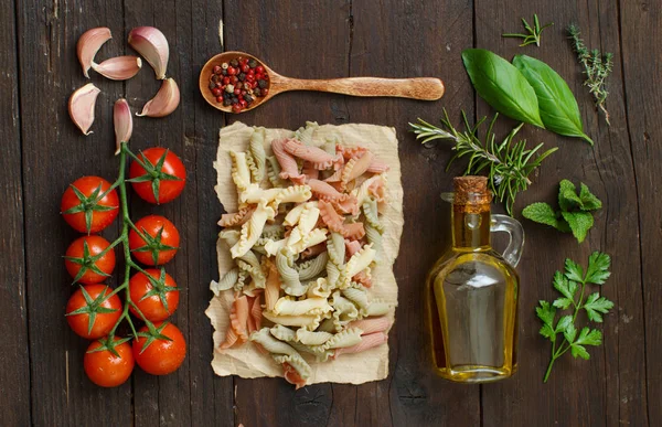 Tricolor pasta, vegetables, herbs and olive oil — Stock Photo, Image