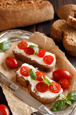 Bruschetta krem peynir, domates ve fesleğen ahşap bir masa üzerinde