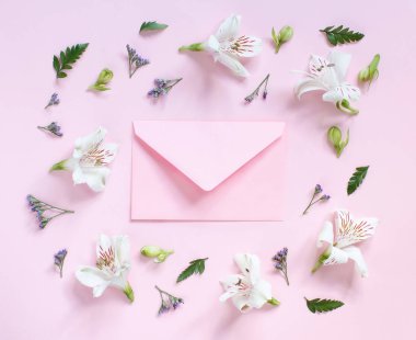 Açık pembe arka planda çiçekler ve zarf