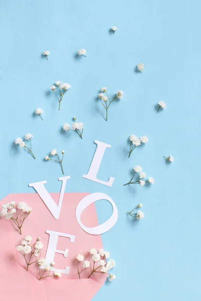 Flores, envelope rosa e palavra Amor sobre um fundo azul claro — Fotografia de Stock