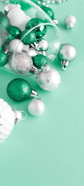 Christmas baubles in a wine glass on a light green background — Stock Photo, Image