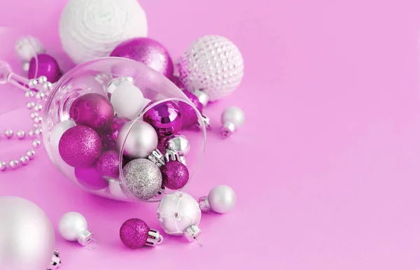 Christmas baubles in a wine glass on a light pink background — Stock Photo, Image