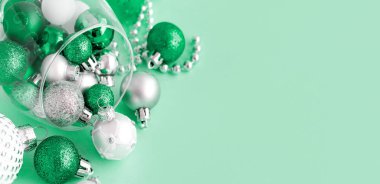 Açık yeşil arka planda şarap kadehinde Noel mücevherleri
