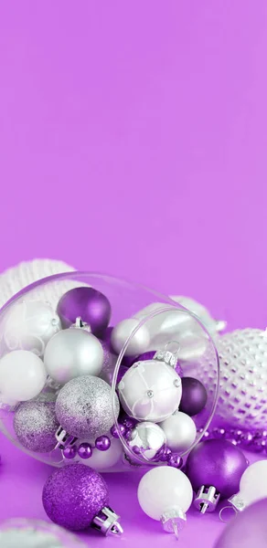 Palline di Natale in un bicchiere di vino su uno sfondo viola — Foto Stock