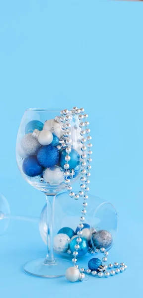 Christmas baubles in a wine glass on a light blue background — Stock Photo, Image
