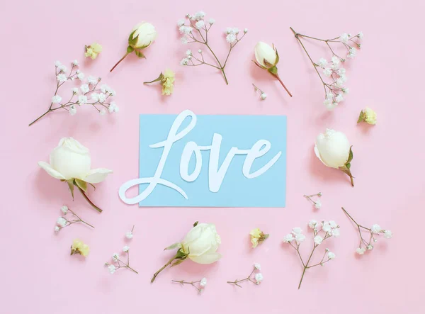 Flowers and word LOVE on a light pink background — Stock Photo, Image