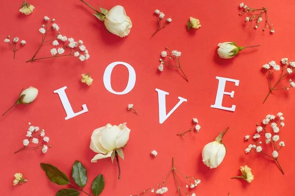 Rosas e palavra AMOR em um fundo vermelho — Fotografia de Stock