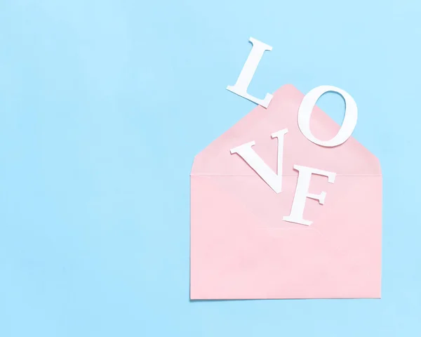Palavra AMOR e envelope rosa em um fundo azul claro — Fotografia de Stock