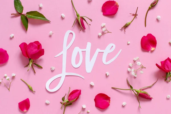 Flores cor de rosa e texto AMOR em um fundo rosa claro — Fotografia de Stock