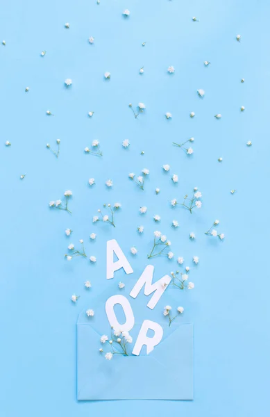 Flores, envelope e texto AMOR em um fundo azul claro — Fotografia de Stock