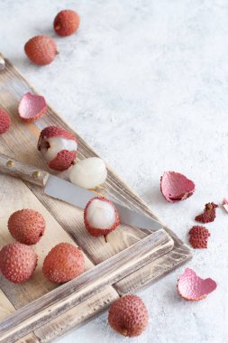 Tahta tepside beyaz bir masada taze litchi meyveleri.
