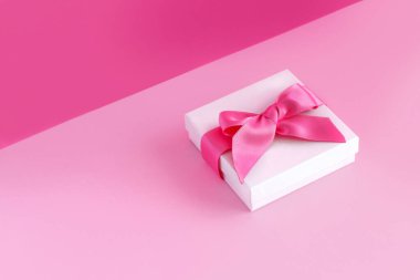 Açık pembe arka planı olan beyaz hediye kutusu.