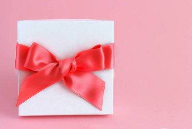 Açık pembe arka planı olan beyaz hediye kutusu.