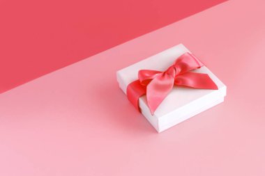 Açık pembe arka planı olan beyaz hediye kutusu.