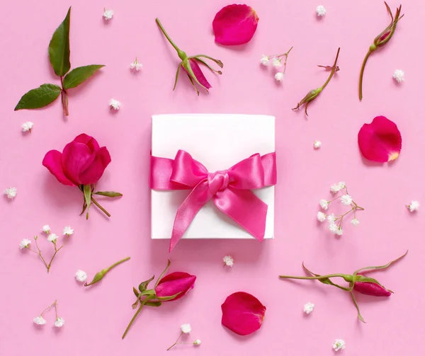 Caja de regalo blanca y flores sobre un fondo rosa claro — Foto de Stock