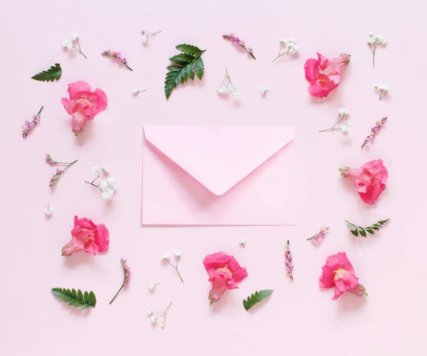 Blumen und rosa Umschlag auf hellrosa Hintergrund — Stockfoto