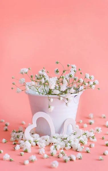 Flores en un cubo y corazones sobre un fondo rosa — Foto de Stock