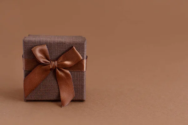 Brązowe pudełko z kokardą na brązowym tle — Zdjęcie stockowe