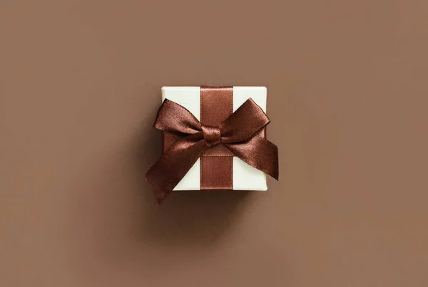 Krem pudełko z brązowym łukiem na brązowym tle — Zdjęcie stockowe