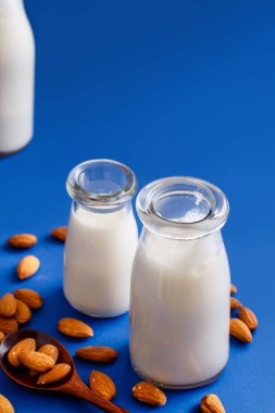 Vejetaryen badem sütü, sütsüz, mavi arka planda.