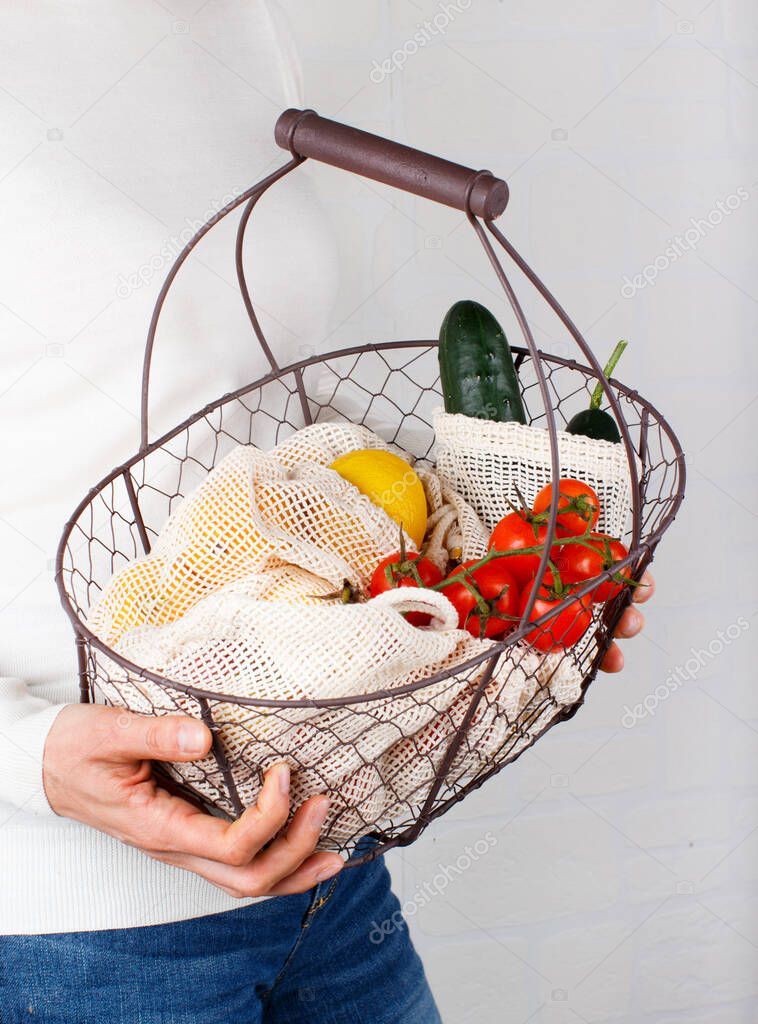 Woman keeps backet with fresh vegetables and fuits  in textile  bags