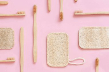 Organik bambu diş fırçaları ve pembe arka planda bulaşık süngerleri ile oluşturulmuş yerleşim planının üst görüntüsü 