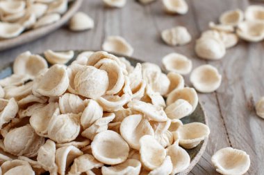 Taze çiğ apulian makarna orekşisi kepekli undan yapılmış koyu bir masada yakın plan.