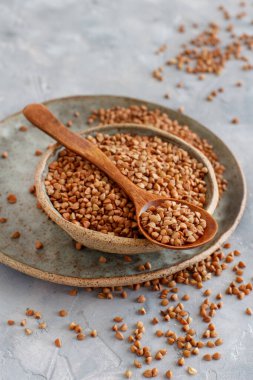 Kaşıkla bir kasede çiğ karabuğday taneleri. 