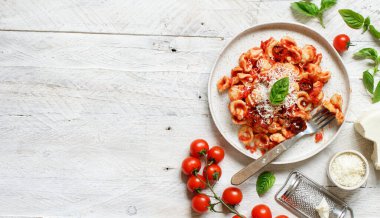 Beyaz ahşap masa üzerinde domates soslu ve cacioricotta peynirli Güney İtalya makarnası.