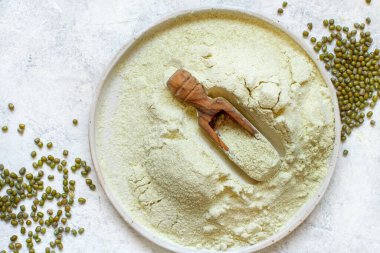 Mung fasulye unu ve tahıl bir tabak üzerinde tahta kaşık üst görüşü, alternatif un