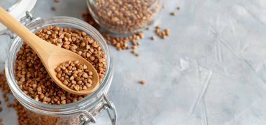 Kavanozda çiğ karabuğday taneleri ve kaşıkla yakın çekim. 