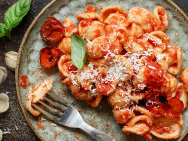 Domates soslu Güney İtalya makarnası ve ahşap bir masa üzerindeki Cacioricotta peyniri manzaralı.