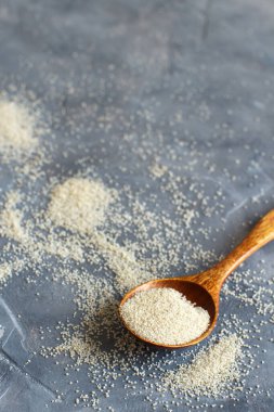 Çiğ pişmemiş fonio tohumları ve gri arkaplan üzerinde bir kaşık fotokopi alanı ile yakın çekim