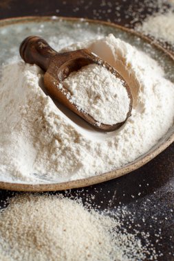 Çiğ fonio unu ve koyu arka planda kaşıkla tohumlar. Alternatif un