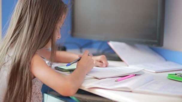 Lány iskoláslány csinál házi feladatot. Lány megtanulja a leckét. használ smartphone — Stock videók