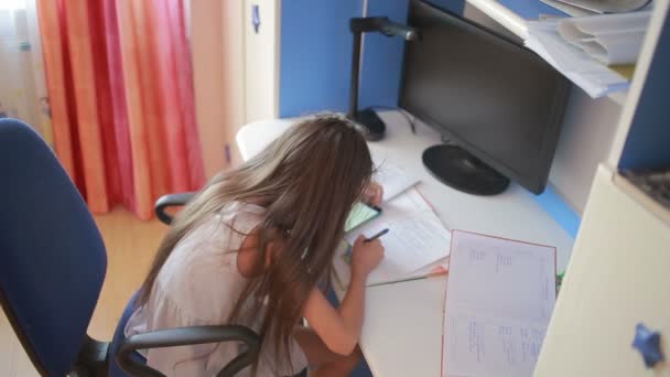 Colegiala haciendo la tarea. La chica aprende lecciones. usando smartphone — Vídeos de Stock