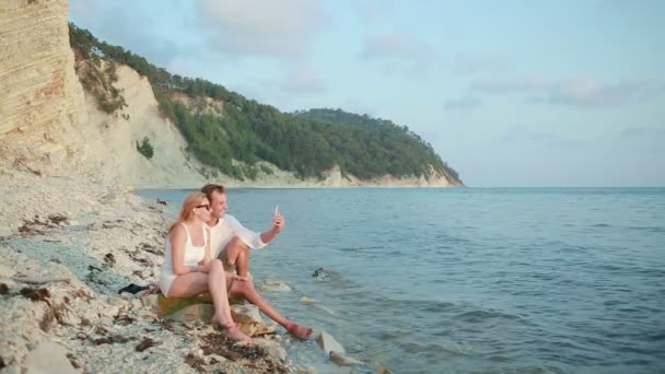 Pareja enamorada en la playa. hacer una videollamada en su smartphone — Vídeos de Stock