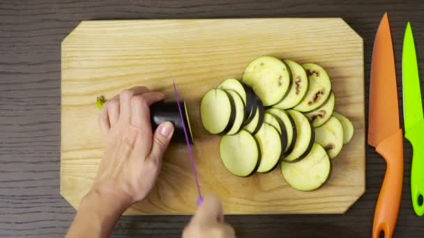 Handen van vrouw snijden aubergine op houten bord. van bovenaf bekijken — Stockvideo