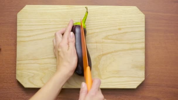 Handen van vrouw snijden aubergine op houten bord. van bovenaf bekijken — Stockvideo