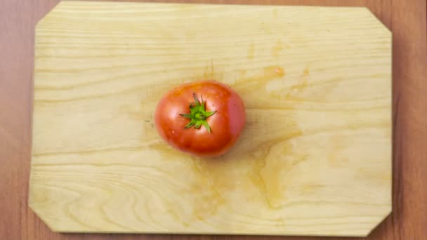 Mujer corta un tomate en una tabla de madera. vista desde arriba — Vídeo de stock