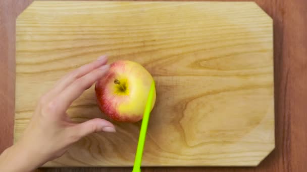 Frau schneidet einen Apfel auf ein Holzbrett. Essen kochen — Stockvideo