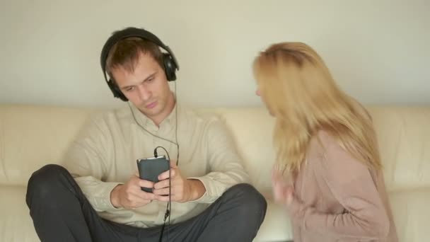 Frau schreit Mann mit Kopfhörer an Ehemann spielt auf dem Smartphone — Stockvideo
