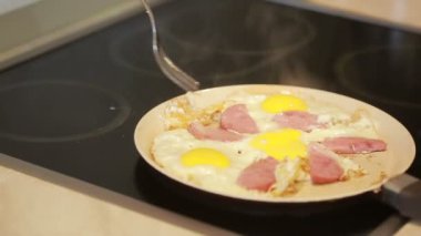 sahanda yumurta ve jambon kahvaltı için bir tavada. Pişirme