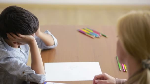 Jeune garçon assis en silence lors d'une séance avec un jeune psychologue . — Video