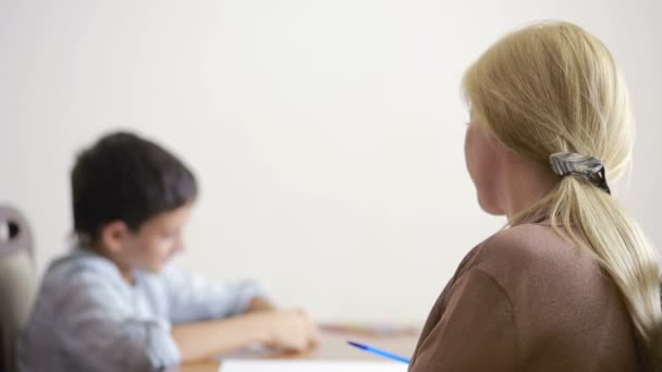 Jeune garçon assis en silence lors d'une séance avec un jeune psychologue . — Video