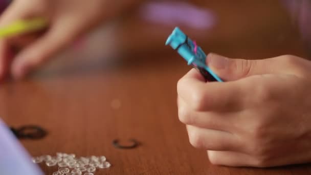 Menina tecer pulseira de elásticos. Faixas de borracha coloridas para tecelagem — Vídeo de Stock