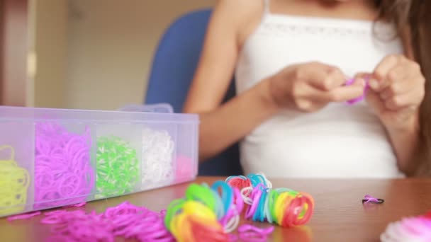 Niña teje pulsera de bandas elásticas. Bandas de goma de colores para tejer — Vídeos de Stock